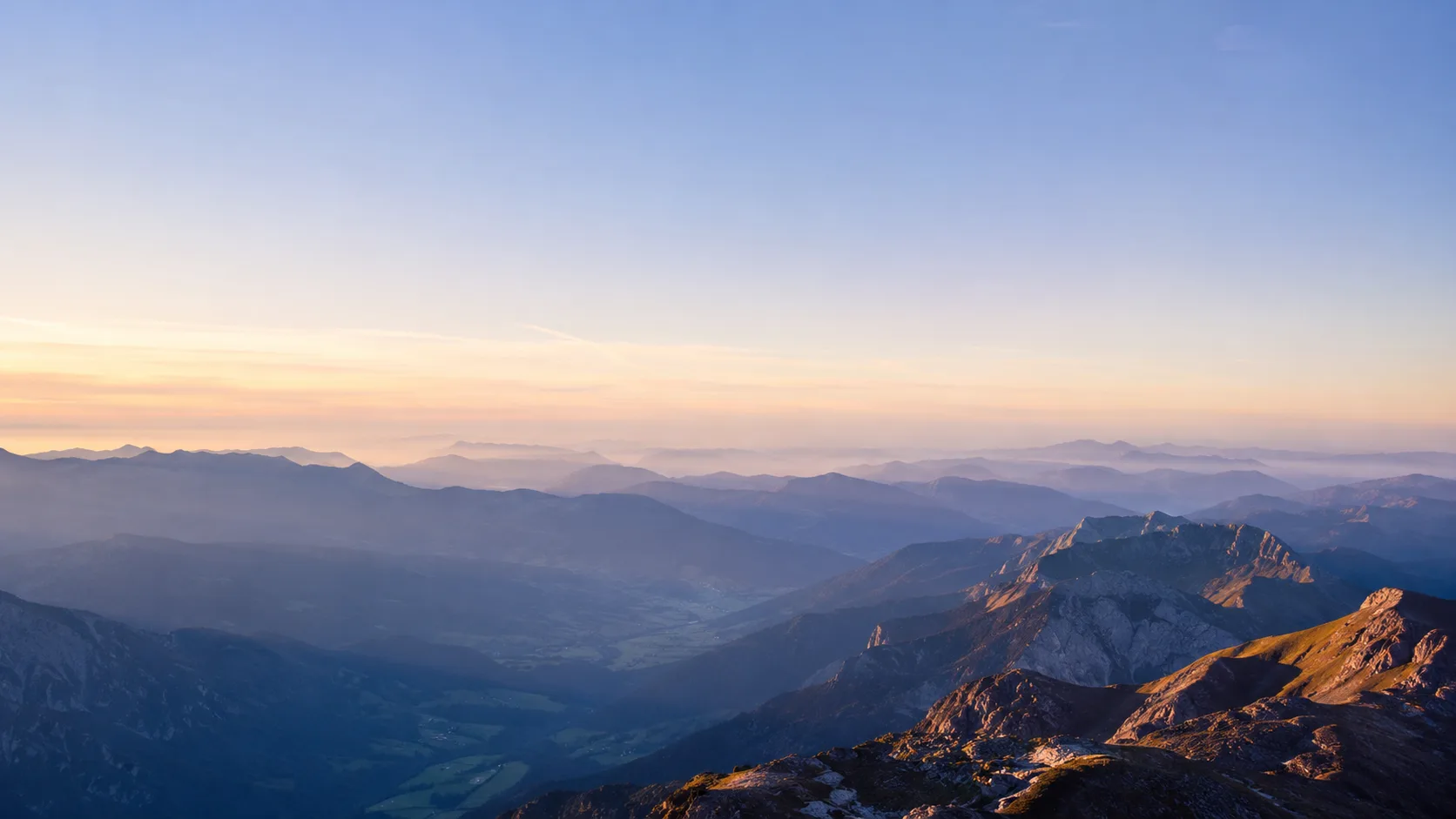 Editorial landscape photograph of a layered mountain range fading into haze at dawn