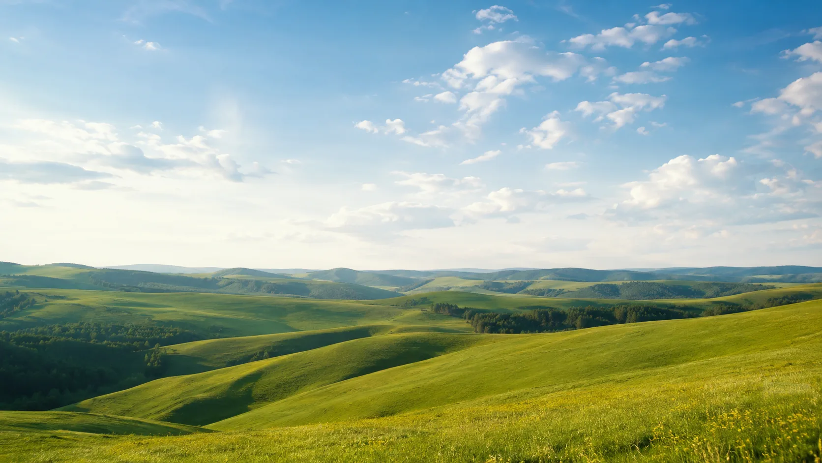 Editorial landscape photograph of rolling green hills under a wide cloud-scattered sky