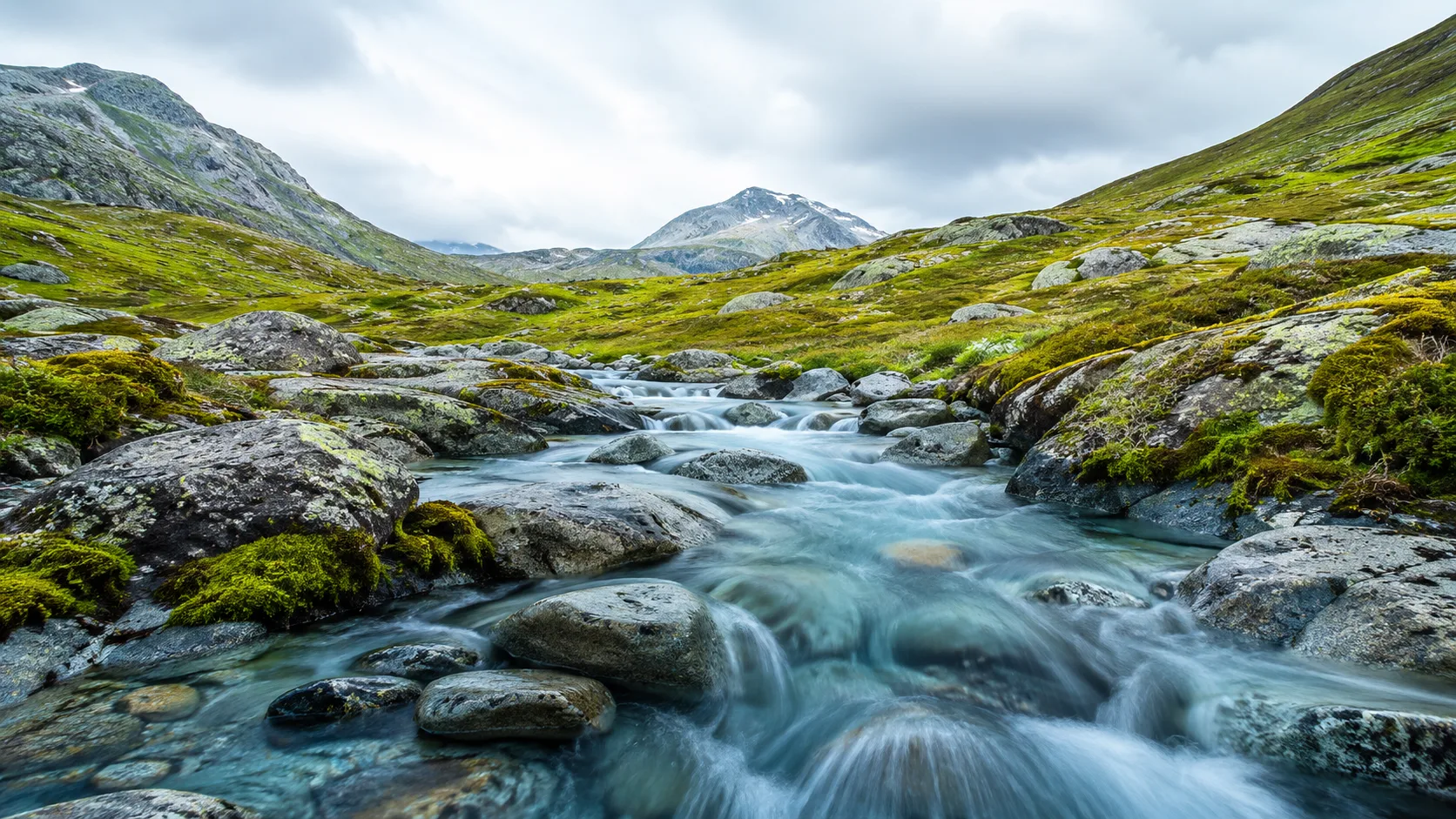 Editorial landscape photograph of a clear rocky mountain stream over smooth stones
