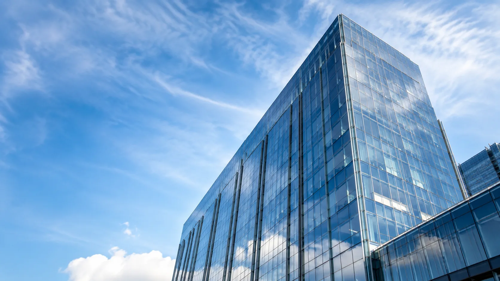 Editorial architecture photograph of a modern glass office tower with a sleek curtain-wall facade