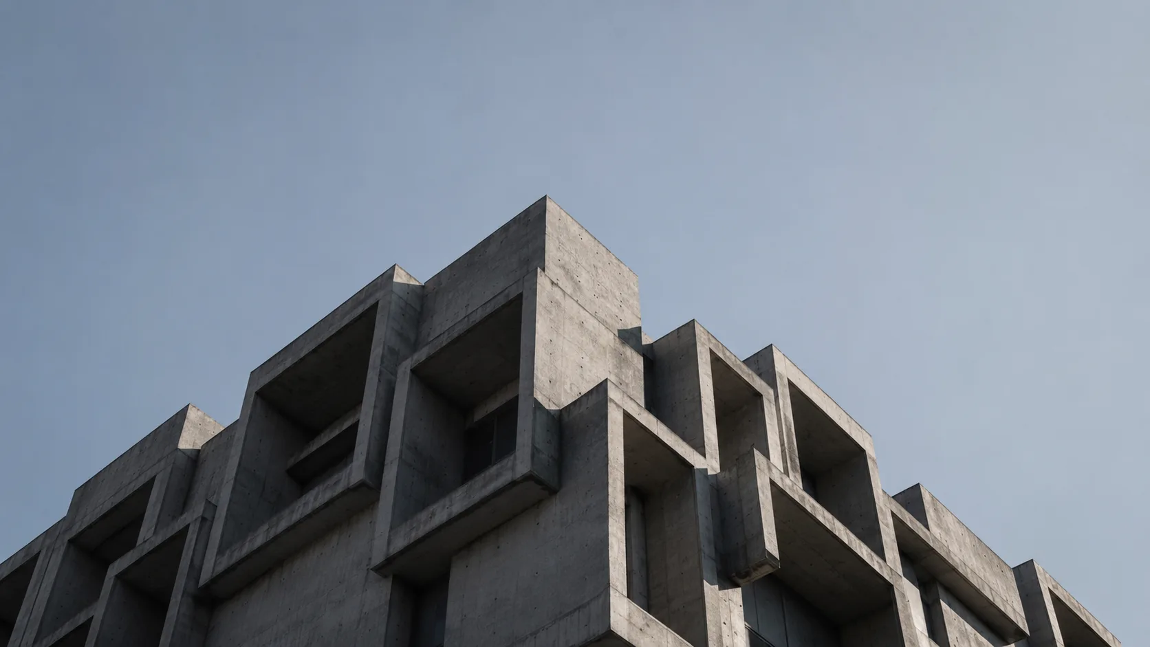 Editorial architecture photograph of a brutalist building facade in bold raw concrete