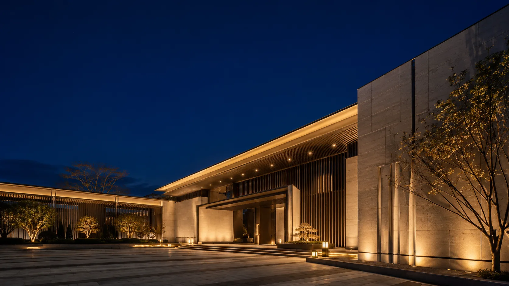 Editorial architecture photograph of a modern building facade lit warm at night