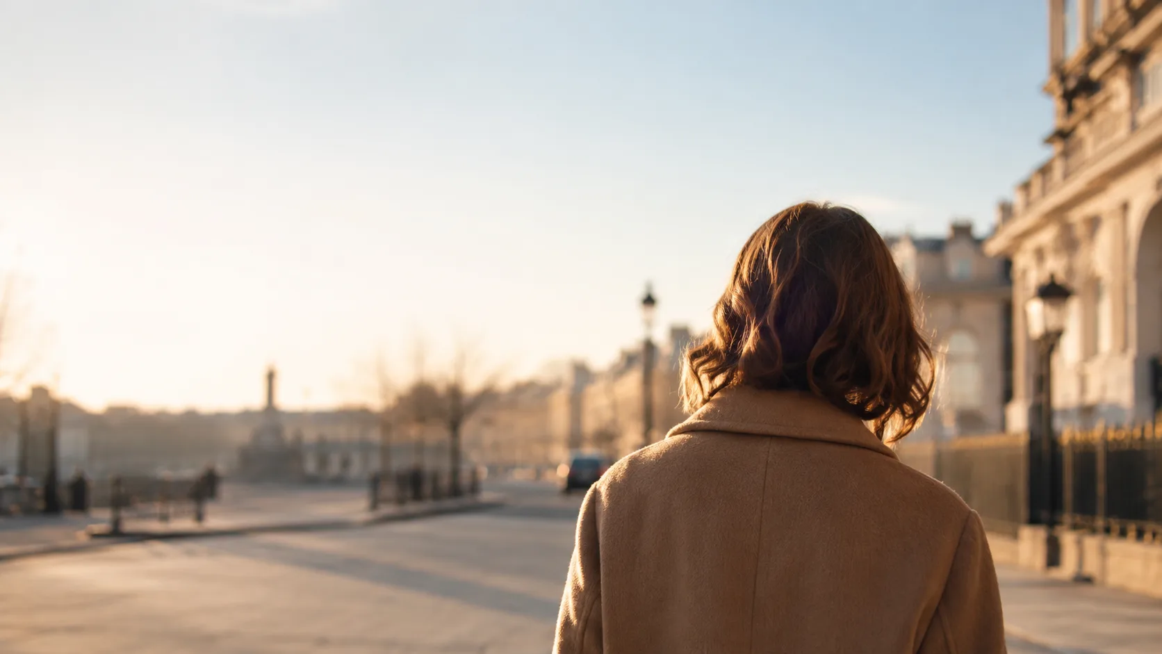Editorial lifestyle photograph of a figure from behind walking down a quiet sunlit street