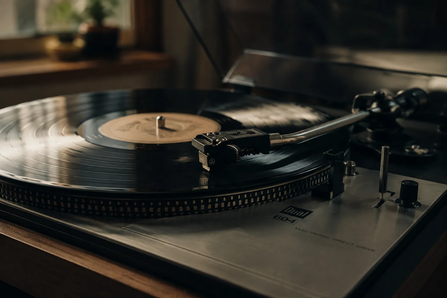 Editorial music macro of a black vinyl record on a vintage turntable with the needle resting on the grooves in warm window light