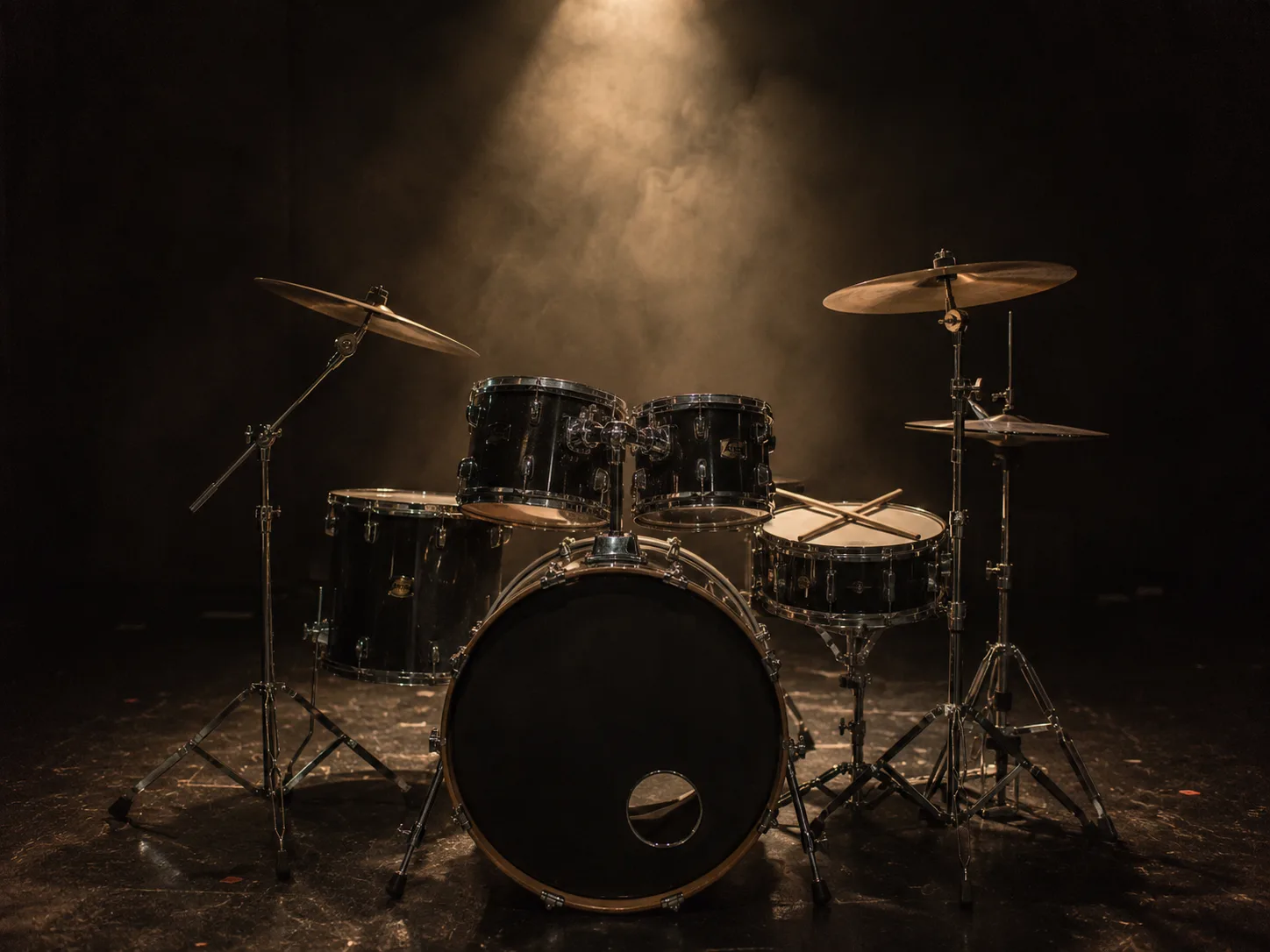 Editorial music wide photograph of a full drum kit on a dim stage with a single warm spotlight, smoke in the beam and crossed sticks on the snare