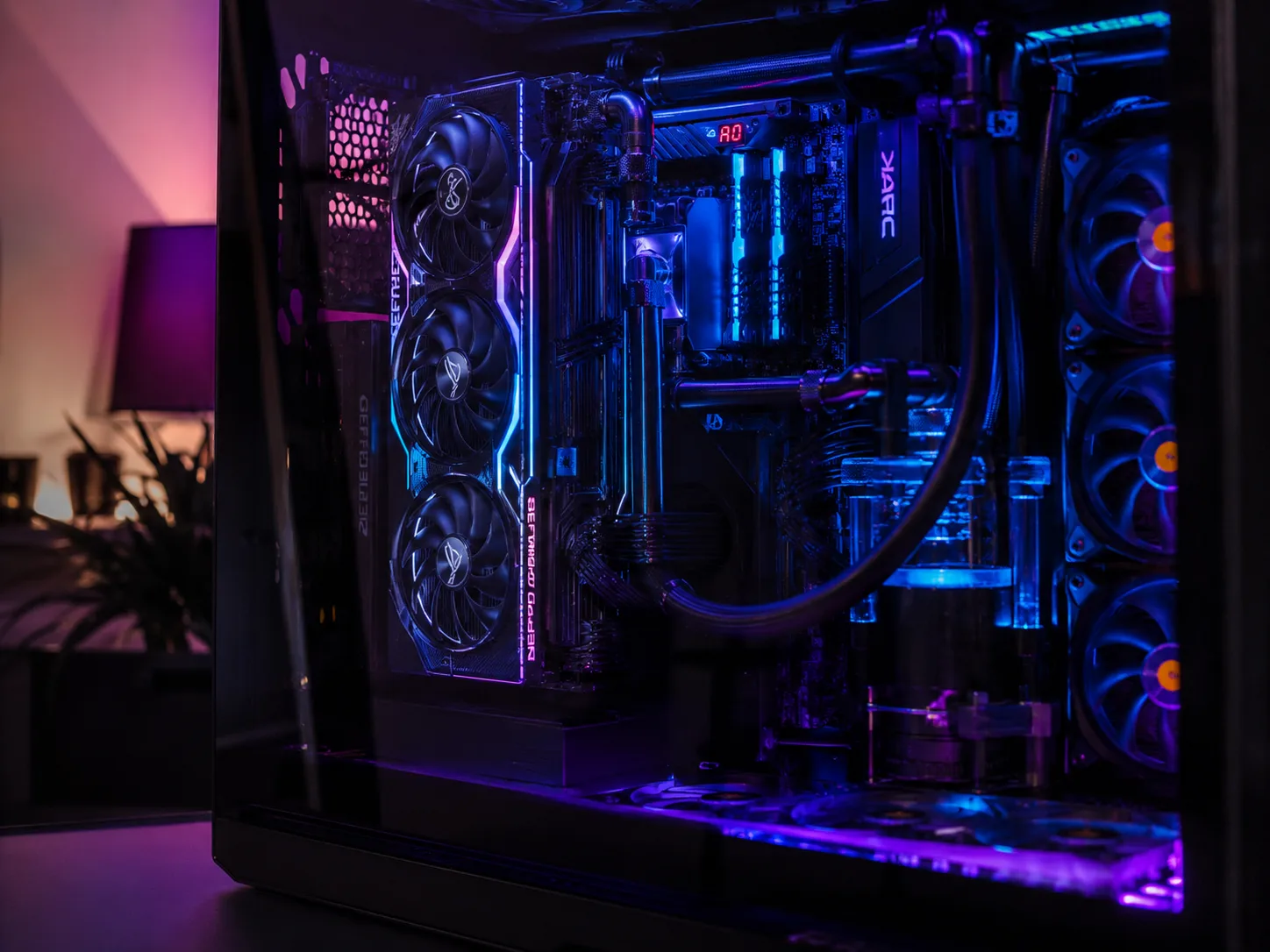 Editorial gaming macro of a custom-built gaming PC interior with RGB GPU fans, liquid cooling tubes and a tempered glass side panel