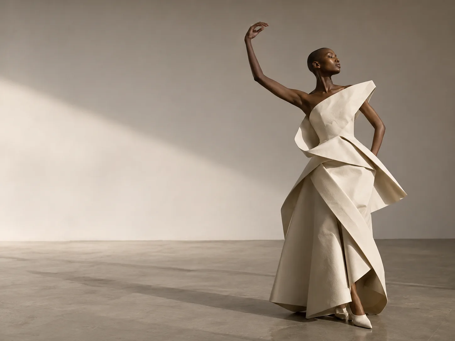Sculptural avant-garde editorial of model in ivory architectural dress in empty gallery